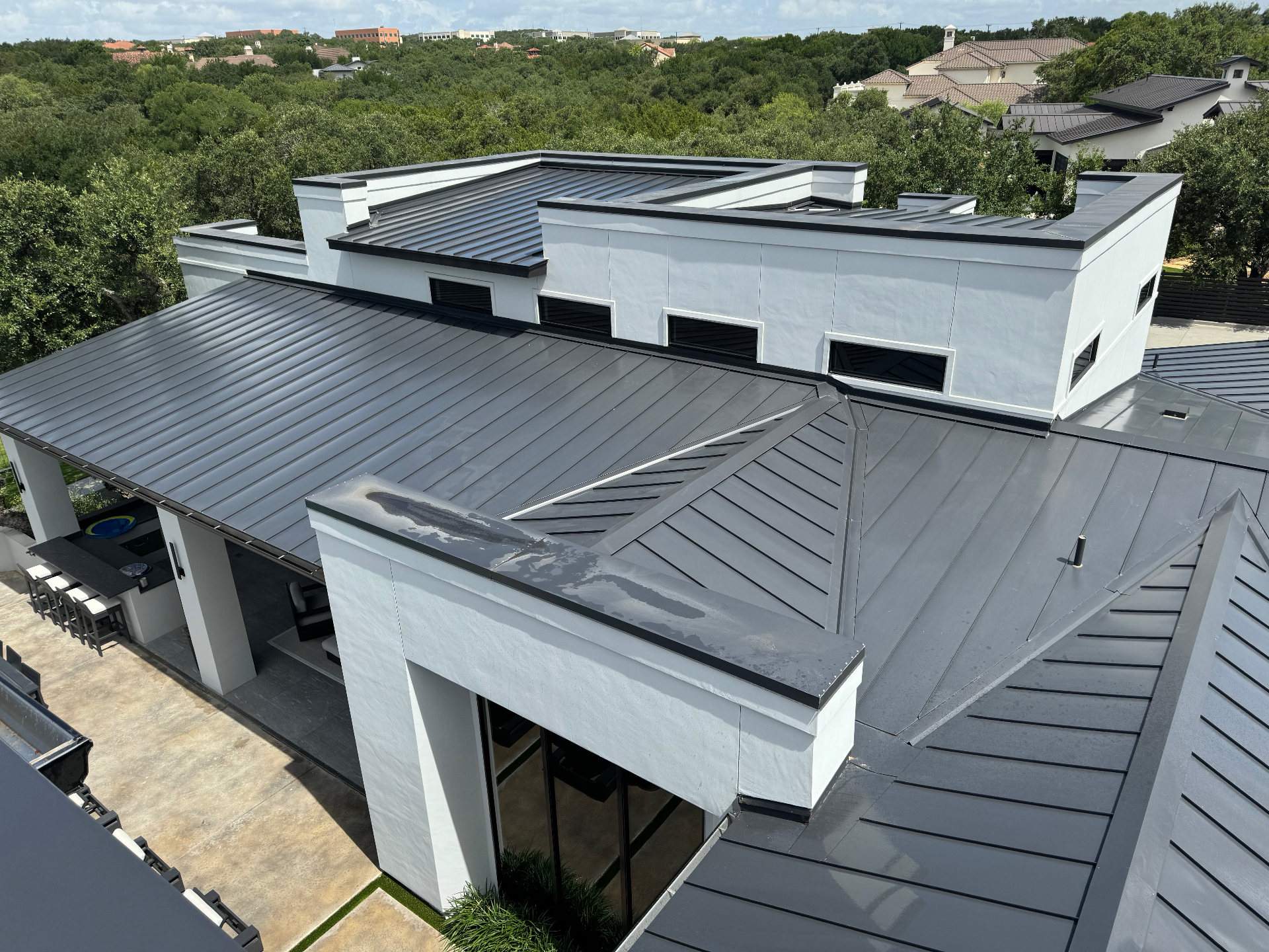 A modern standing-seam metal roof on a white stucco home in San Antonio, showing the clean, uniform finish that professional metal roof cleaning can restore.