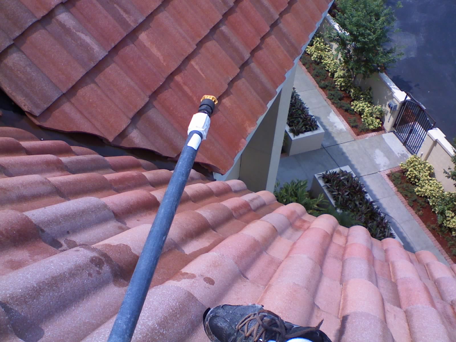 Long-pole soft wash applicator reaching across a tile roof at Axe Retirement, showing how we clean high, steep sections from a safe stance