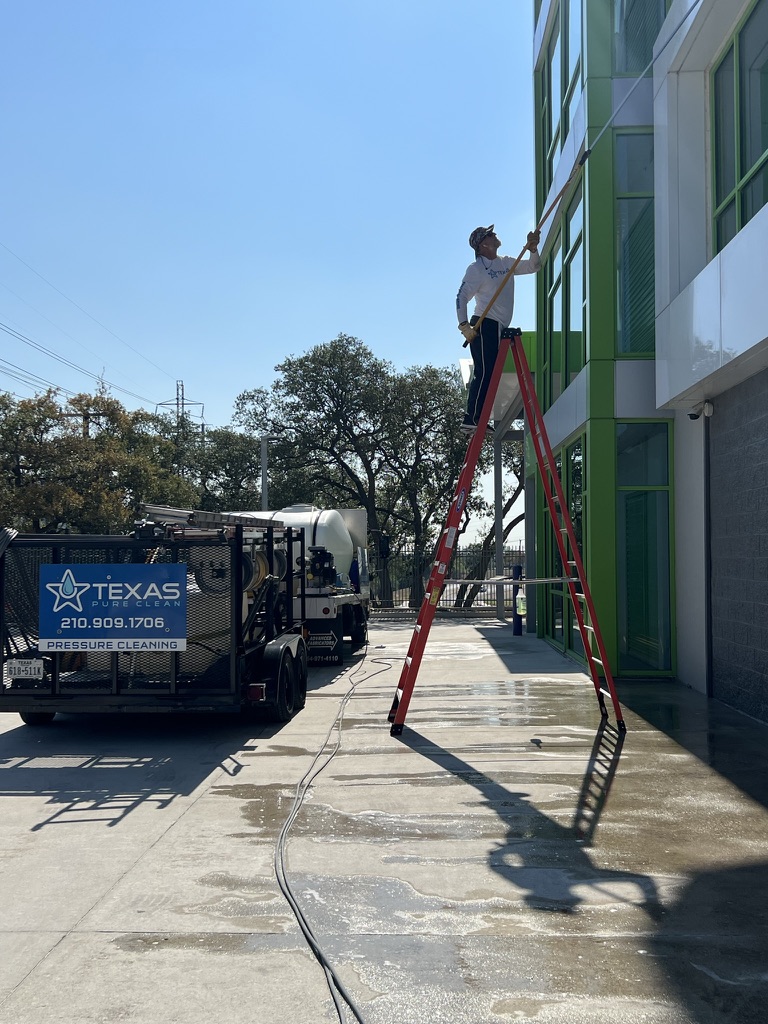 Texas Pure Clean technician cleaning windows and building exterior at Key Mini Storage