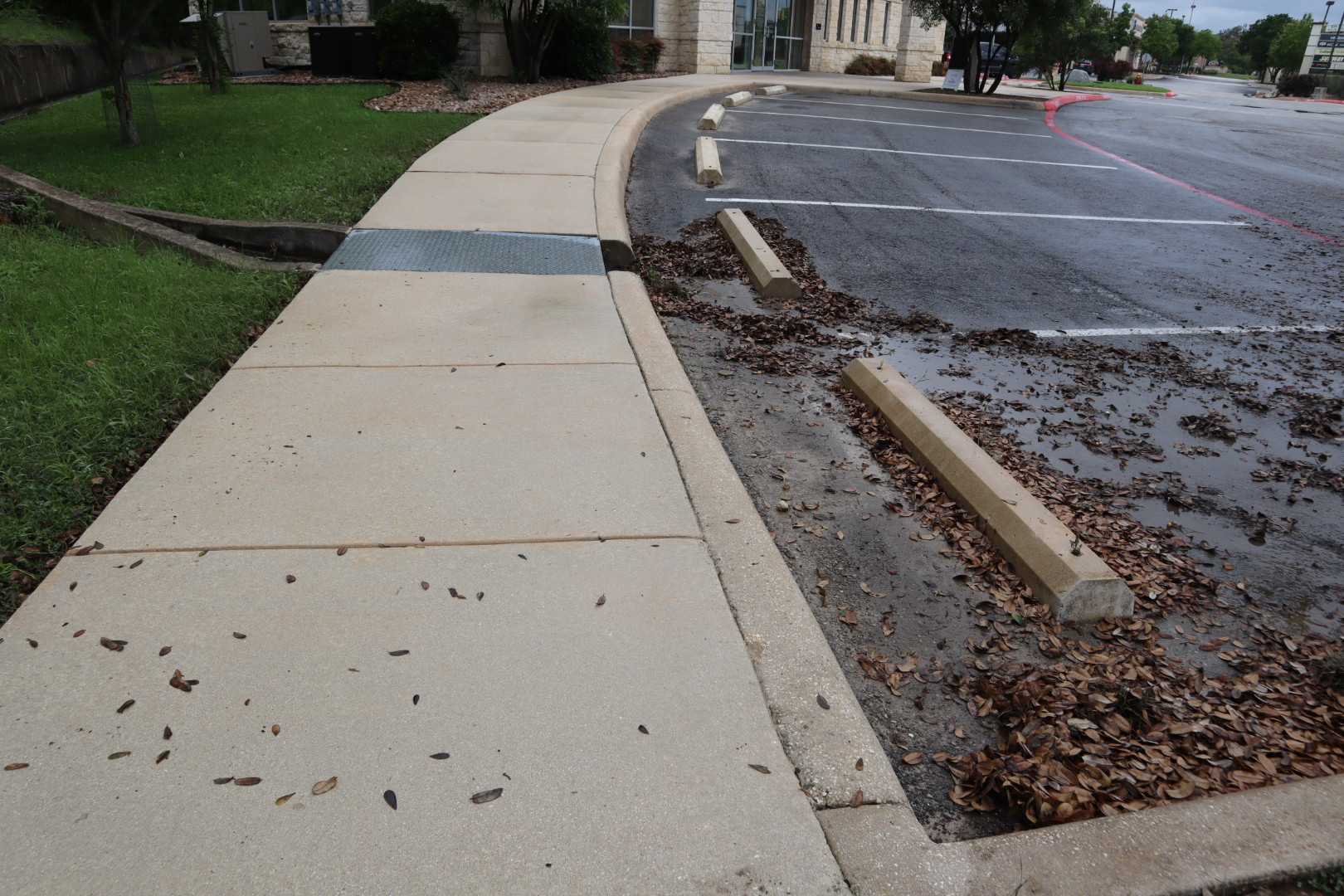 Curved sidewalk and curbs along the credit union after cleaning, with the concrete brought back to a bright, uniform finish along the fire lane