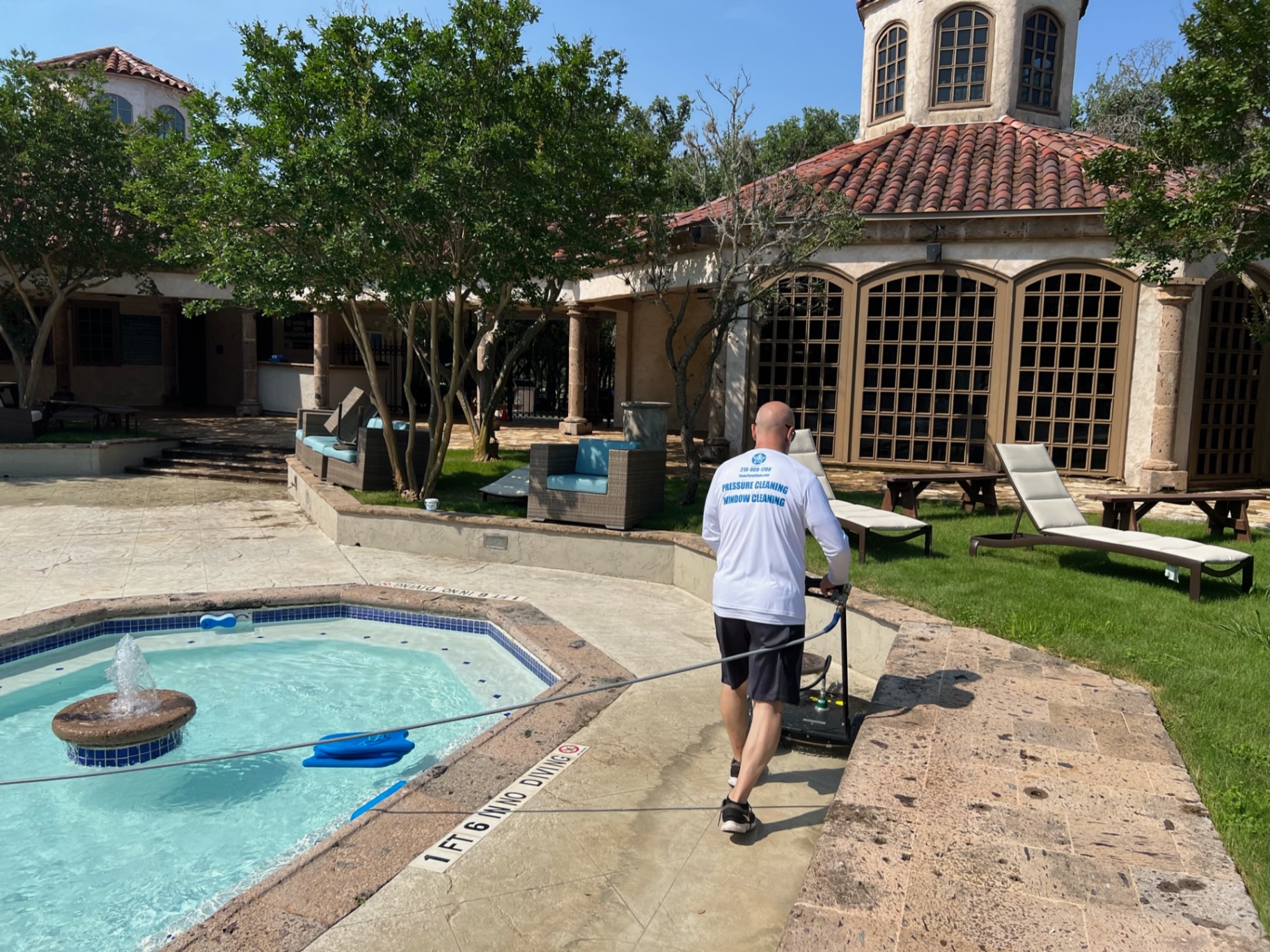 Cleaning the spa surround and pool coping with a surface cleaner staged nearby for the larger deck sections.