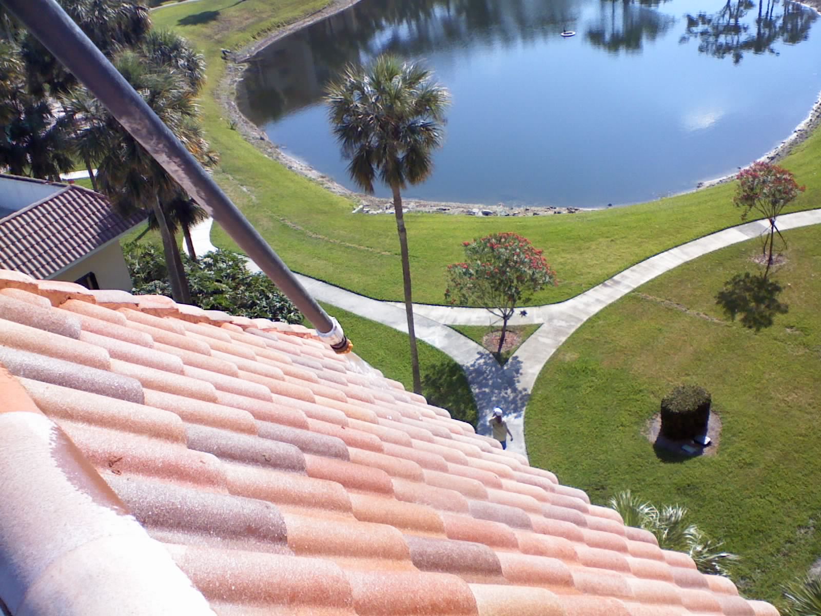View down the length of a tile roof at Axe Retirement showing color restored across the field of tile, with the property landscape and lake visible below