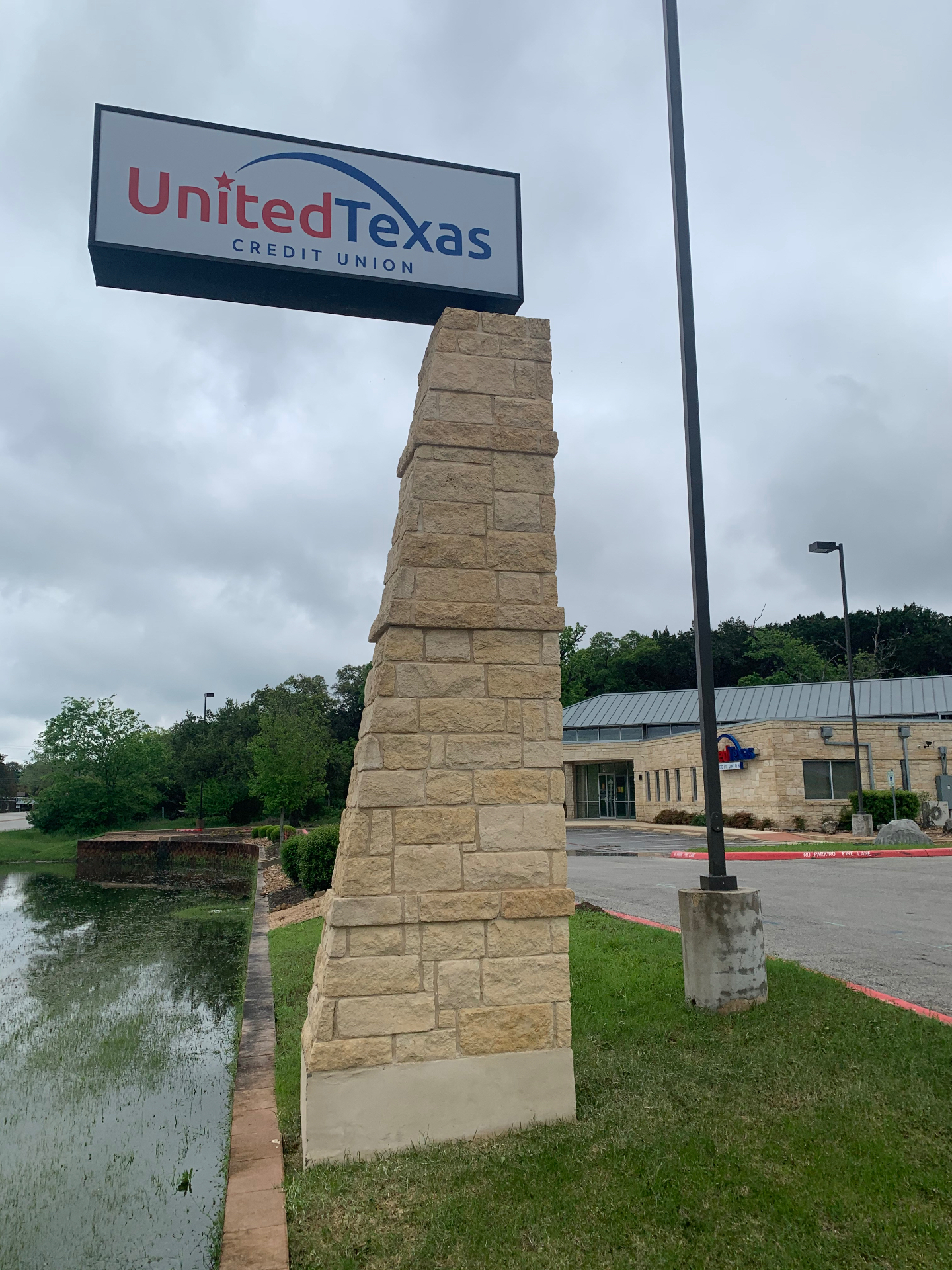 Monument sign for United Texas Credit Union in Boerne after cleaning, with the stone column brought back to a clean, natural Hill Country color