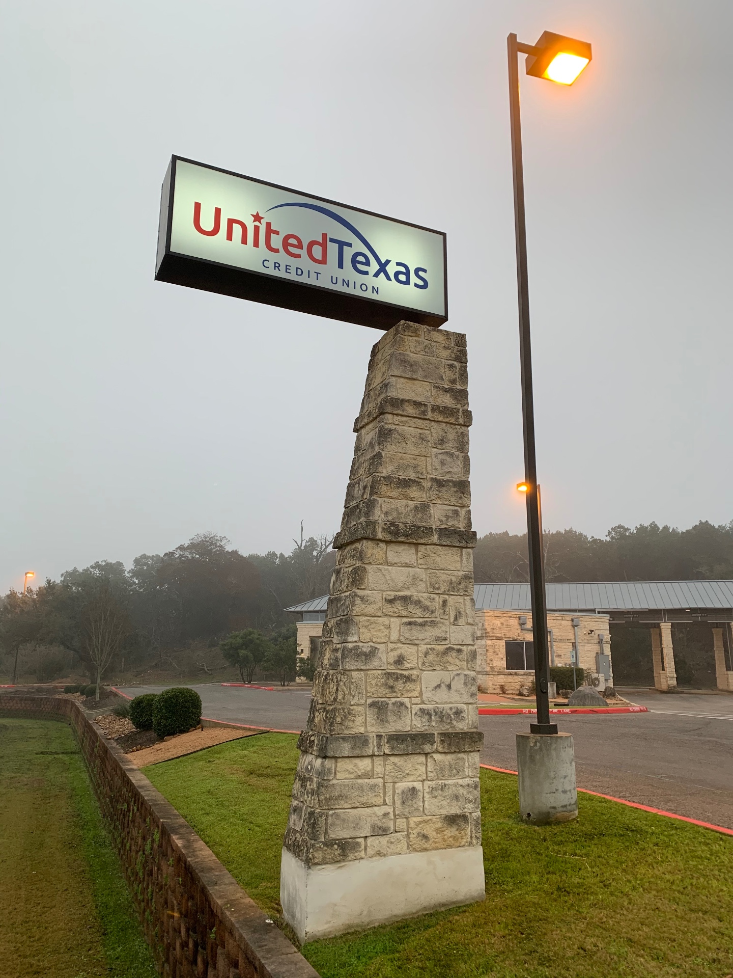 Monument sign for United Texas Credit Union in Boerne before cleaning, with heavy black algae and mildew staining on the stone column