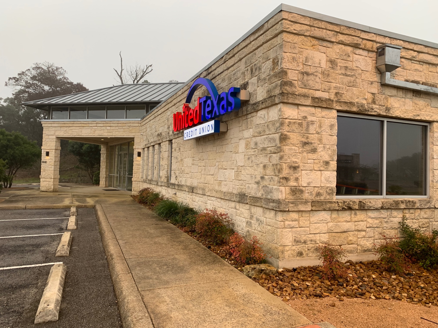 United Texas Credit Union in Boerne before cleaning — Hill Country limestone building on Main Street with visible algae staining on the stone and signage