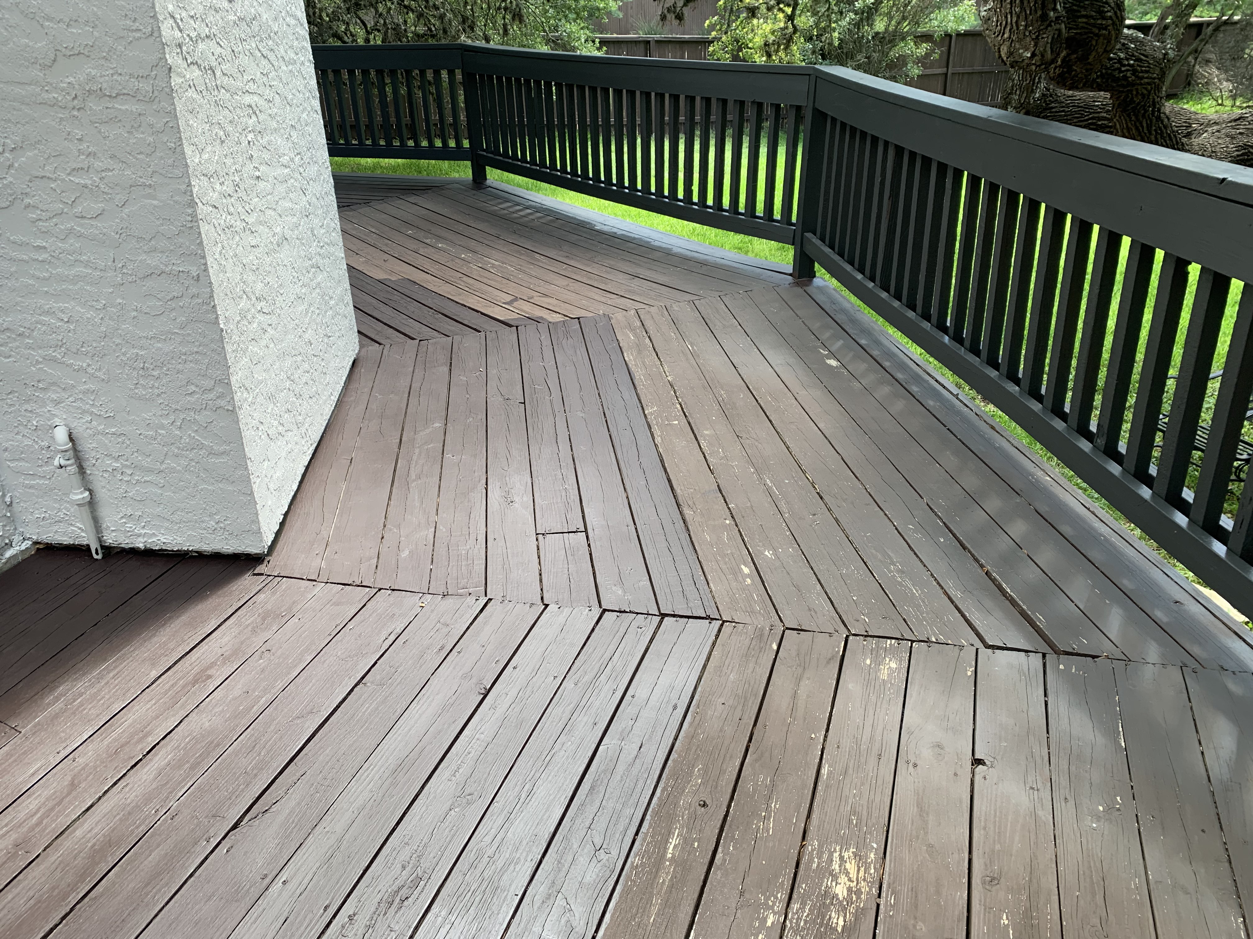 Section of the deck showing patches with no paint left at all, just raw, tired wood exposed to the elements